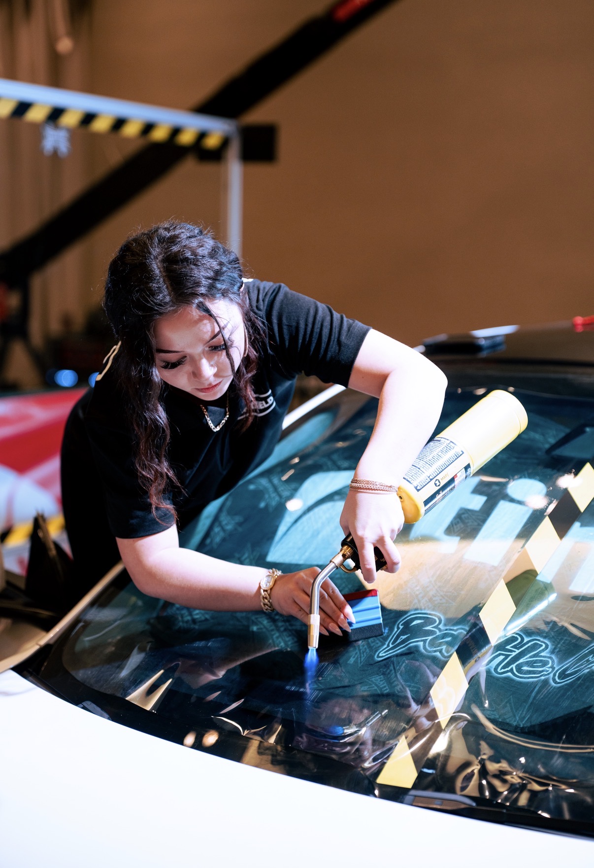 Owner of Nfamous Customs heat-shrinking window film onto a windshield in her Sisters, Oregon shop