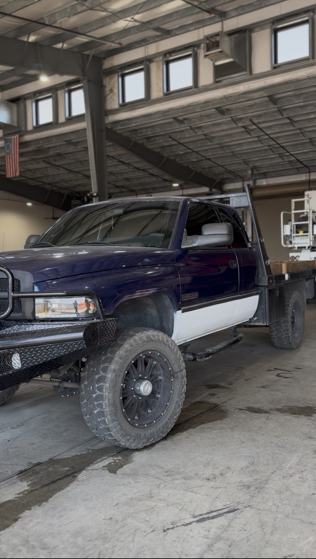 Lifted blue Dodge Ram 2500 flatbed with limo-dark tint inside the install bay
